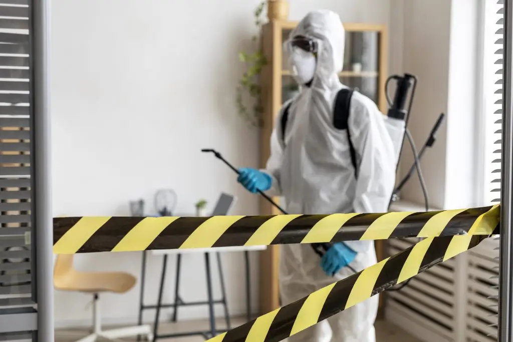 Person in protective gear disinfecting area